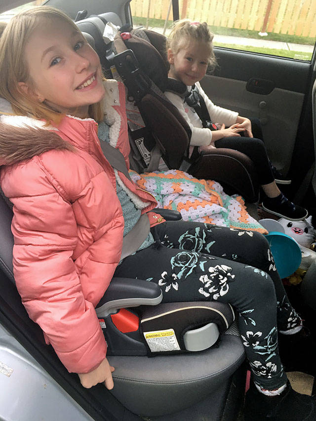Evelyn Renner, 9, and Hazel Renner, 4, sit in their booster and child car seats, respectively. Updated requirements to Washington’s child car restraint law now specify that a child younger than 13 who is not 4 feet, 9 inches, must use a booster seat. (Lena Renner)