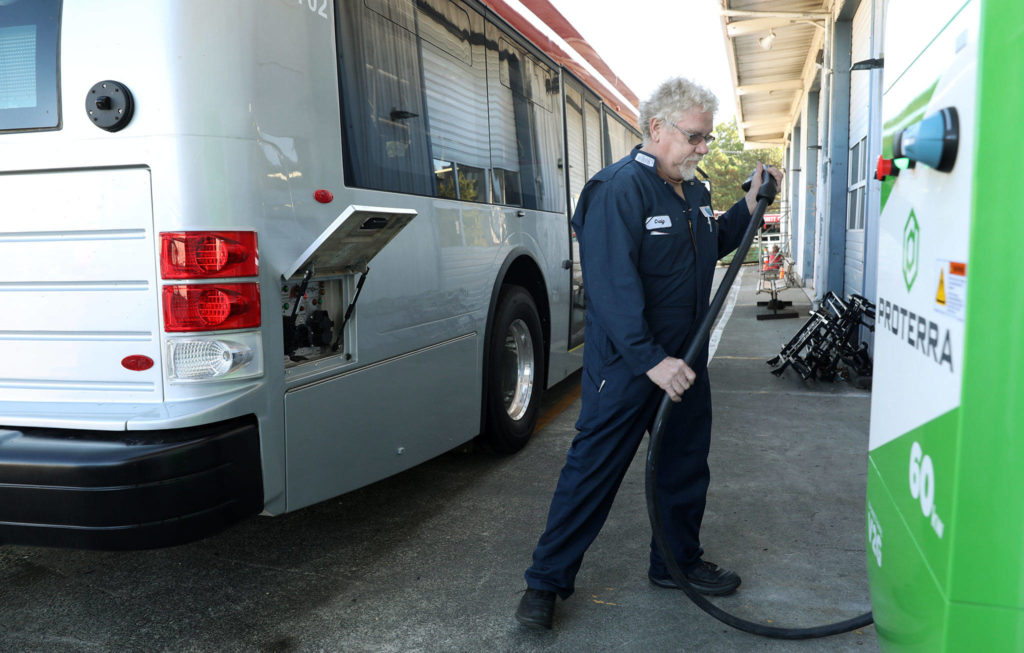 Craig Jacobsen, a technician at Everett Transit, demonstrates how the electric buses are charged in 2018. (Lizz Giordano / Herald file)
