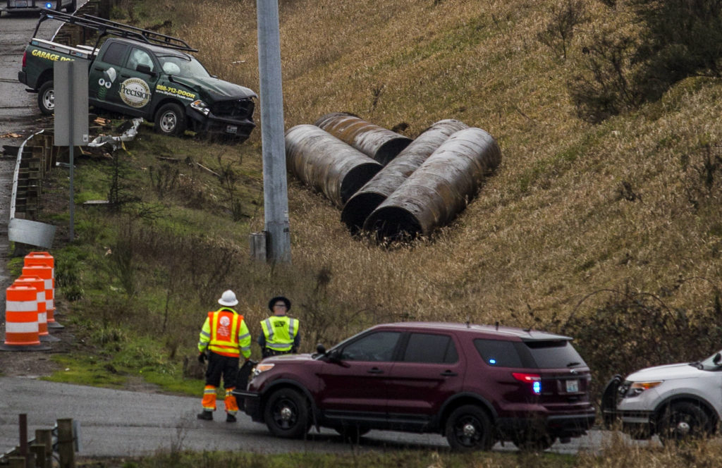 A truck sits in a ditch off of the northbound I-5 lanes, where it went through a barricade next to where a semi flipped on Thursday in Lynnwood. (Olivia Vanni / The Herald).
