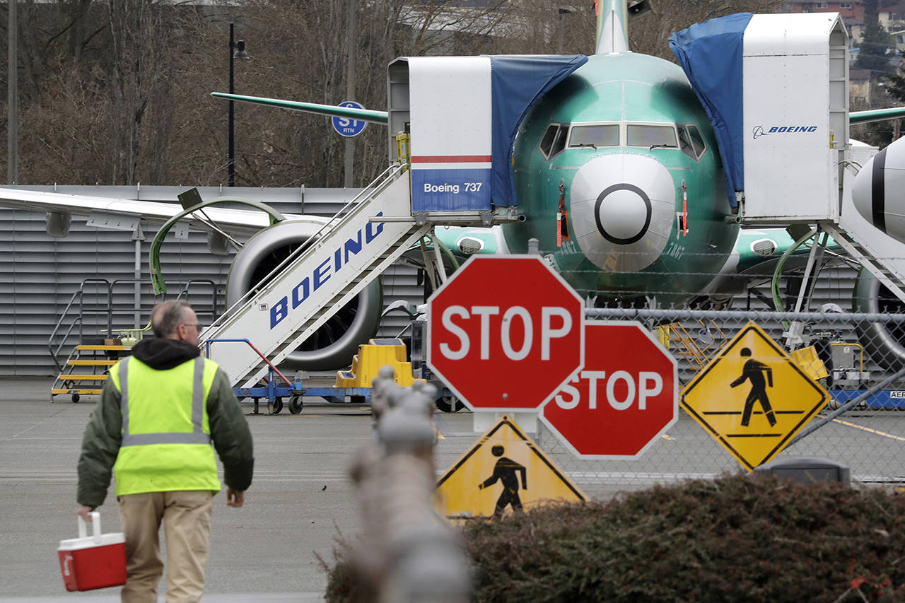 In this Dec. 16 photo, a Boeing worker walks in view of a 737 Max jet in Renton. (AP Photo/Elaine Thompson, File)