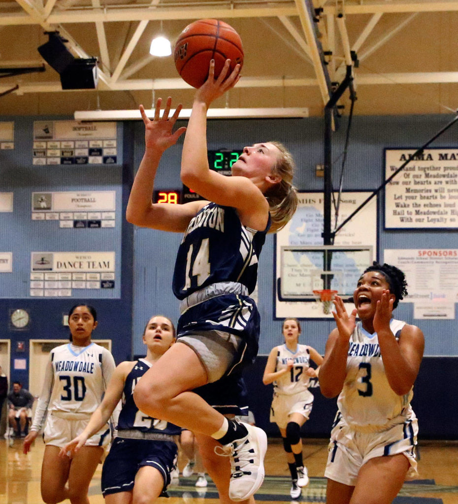 Arlington’s Keira Marsh (center) drives for a layup with Meadowdale’s Alicia Morrison (3) trailing Friday evening at Meadowdale High School in Lynnwood. The Eagles won 61-40. (Kevin Clark / The Herald)
