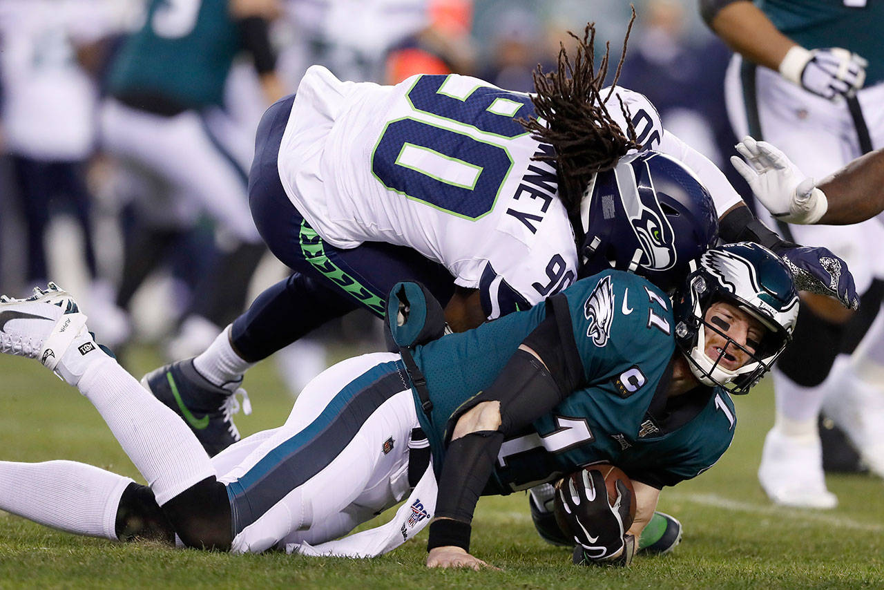 Seattle defensive end Jadeveon Clowney (90) hits Philadelphia quarterback Carson Wentz during the first half of their NFL wild-card playoff game Sunday in Philadelphia. Wentz was injured on the play. (AP Photo/Julio Cortez)