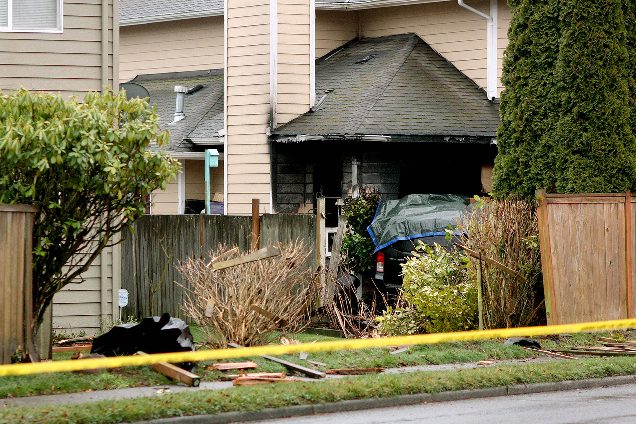 A car crashed through a power pole and into a house in Mountlake Terrace on Monday. A person in the car died, and the accident started a fire at the home. (Zachariah Bryan / The Herald)