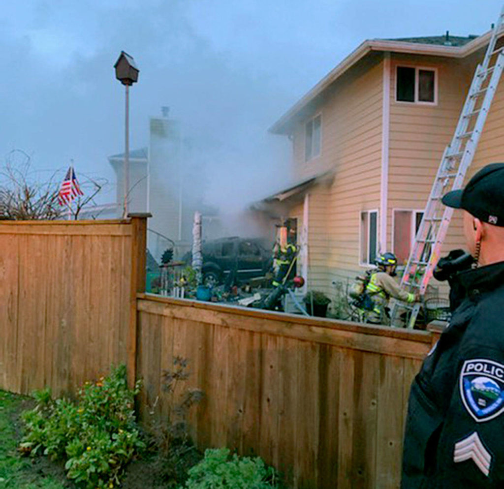 Firefighters work at 220th Street SW and 44th Avenue W in Mountlake Terrace Monday morning after a car sheared a power pole and crashed into a house, starting a fire. One person in the car died. (South County Fire) 
