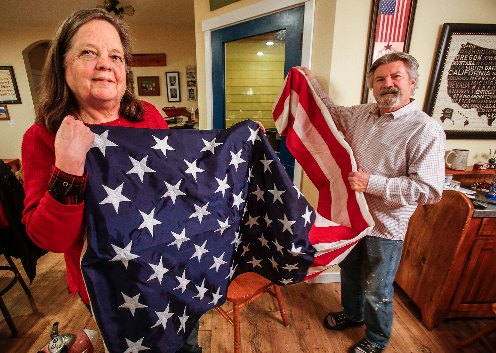 Shellie and Brian Starr unfold a big American flag at their Snohomish home Thursday. It was flown over the USS Theodore Roosevelt on April 20, in honor of their son, Marine Cpl. Jeffrey Starr, who was killed in Iraq in 2005. (Dan Bates / The Herald)