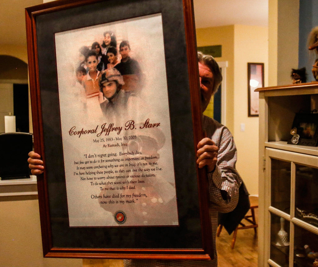 Brian Starr holds up a framed poster that includes images of his son, Marine Cpl. Jeffrey Starr, and children in Iraq. The Marine from Snohomish was killed in Iraq on May 30, 2005. Before he died, he wrote a letter to his girlfriend. Words from that letter are also incorporated on the poster. (Dan Bates / The Herald)
