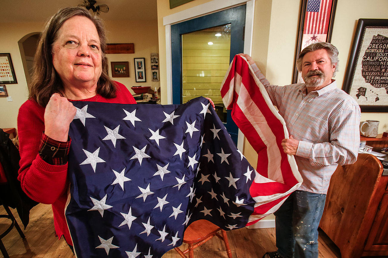 Shellie and Brian Starr unfold a big American flag at their Snohomish home Thursday. It was flown over the USS Theodore Roosevelt on April 20, in honor of their son, Marine Cpl. Jeffrey Starr, who was killed in Iraq in 2005. (Dan Bates / The Herald)