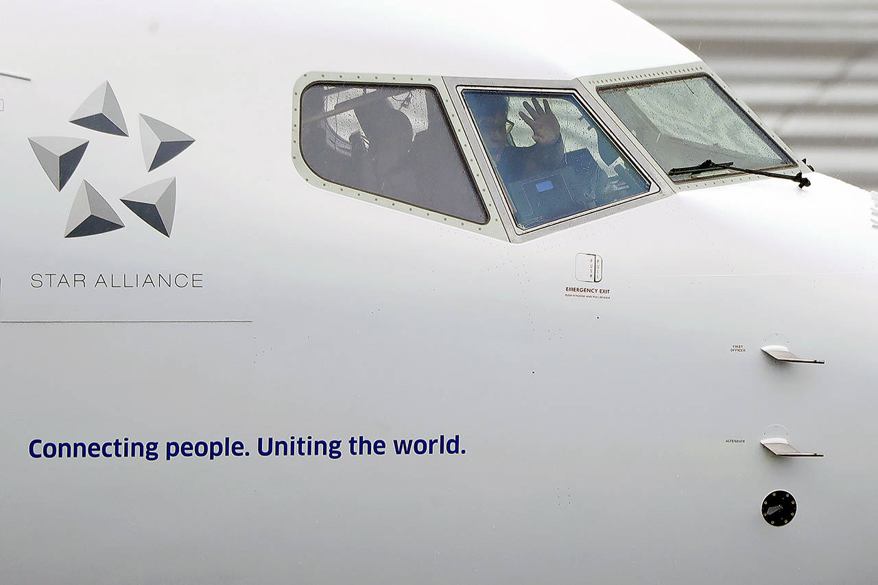 A pilot waves from the flight deck of a United Airlines Boeing 737 Max airplane prior to a flight Dec. 11, 2019, at Renton Municipal Airport in Renton. (AP Photo/Ted S. Warren)