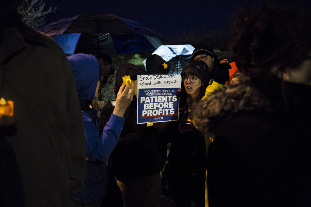 People gather with candles and signs during a union contract negotiation vigil at Northwest Everett Neighborhood Park across from Providence Region Medical Center Everett on Wednesday. (Olivia Vanni / The Herald).
