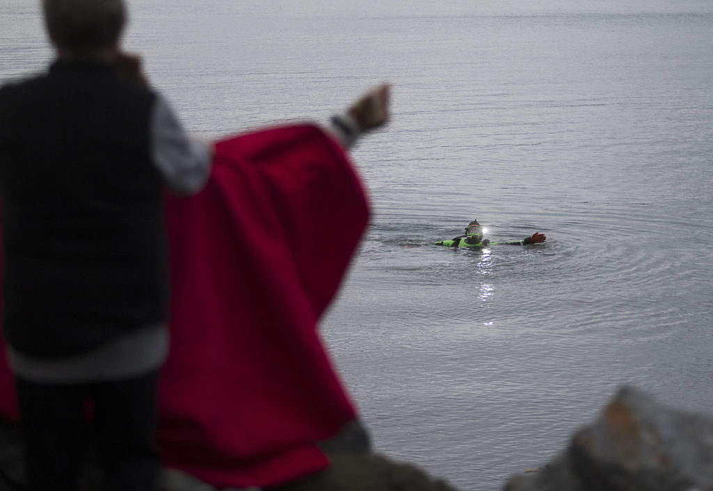 A Snohomish County Sheriffs Office diver uses hand signals to ask an eyewitness to help him during the search for a man who was last seen swimming to shore after his inflatable boat capsized off the beach north of the Mukilteo ferry Wednesday. (Andy Bronson / The Herald)
