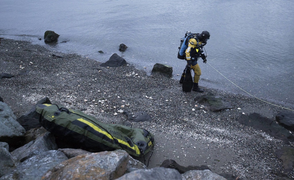 A diver walks past a partially inflated raft before heading into the water to search for a man who was last seen swimming to shore after his inflatable boat capsized off the beach north of the Mukilteo ferry Wednesday. (Andy Bronson / The Herald)
