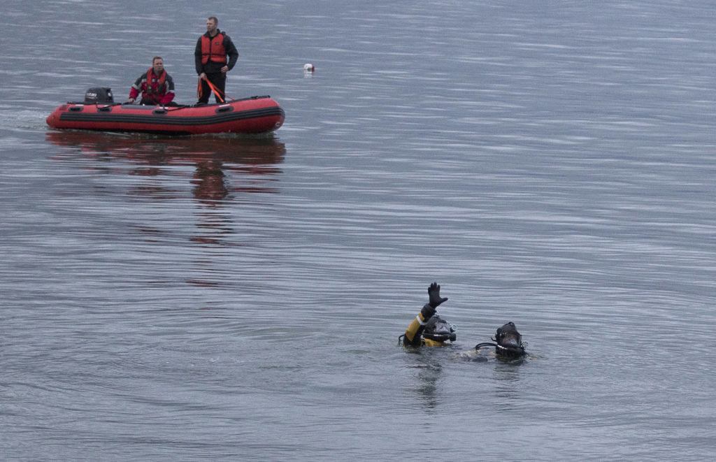 Divers signal before going below in search for a man who was last seen swimming to shore after his inflatable boat capsized off the beach north of the Mukilteo ferry Wednesday. (Andy Bronson / The Herald)
