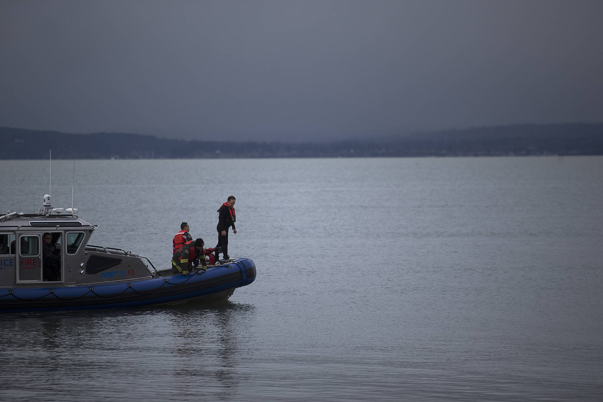 Everett rescue personnel peer over the sides of a boat off the beach north of the Mukilteo ferry on Wednesday. (Andy Bronson / The Herald)