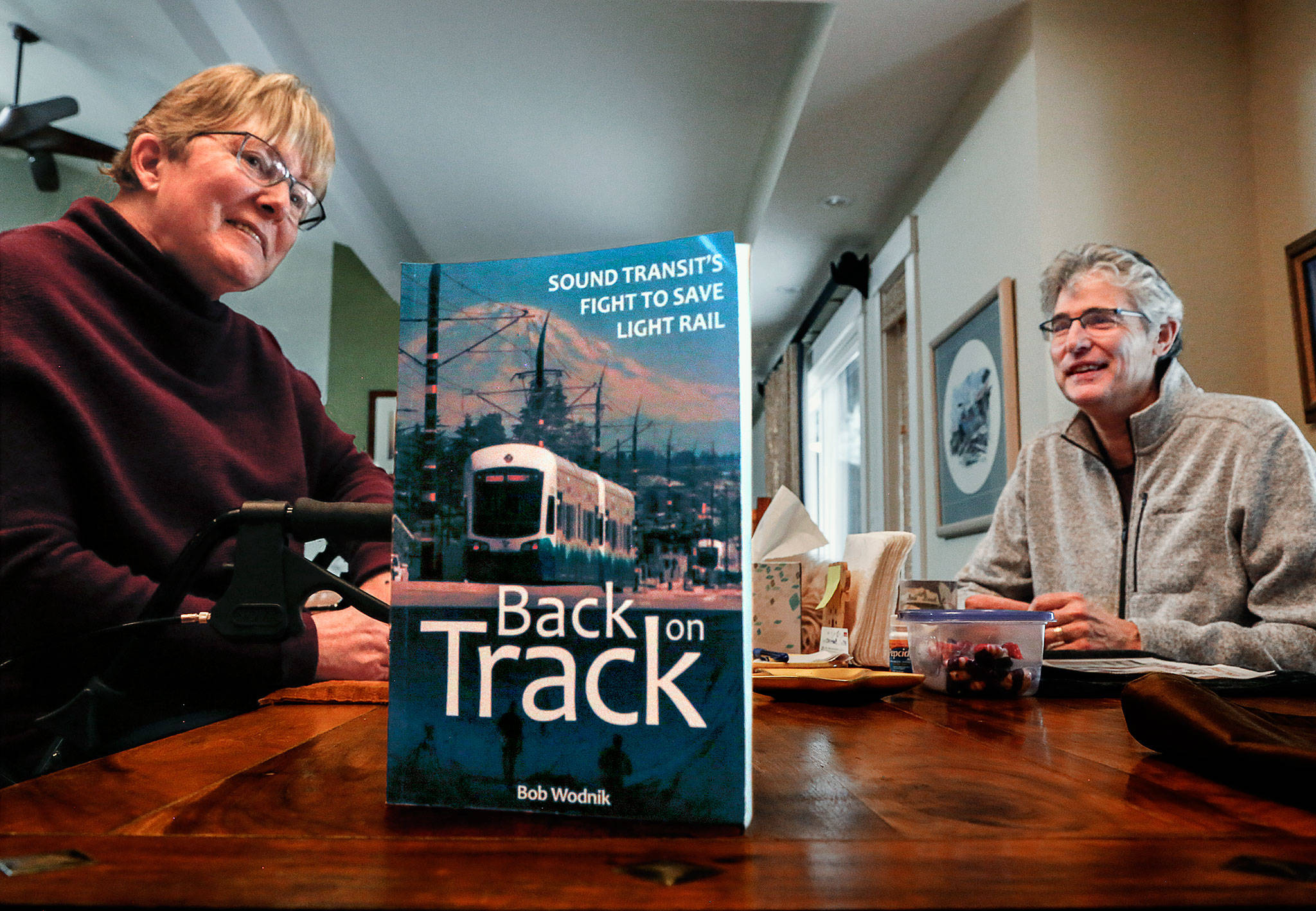 In her Mill Creek area home, Joni Earl, former Sound Transit CEO, and author Bob Wodnik (right) talk about the transit agency’s decades-long effort to bring light rail to the region. Wodnik, a former Herald writer, has written “Back on Track,” a new book about the battles for light rail. (Dan Bates / The Herald)