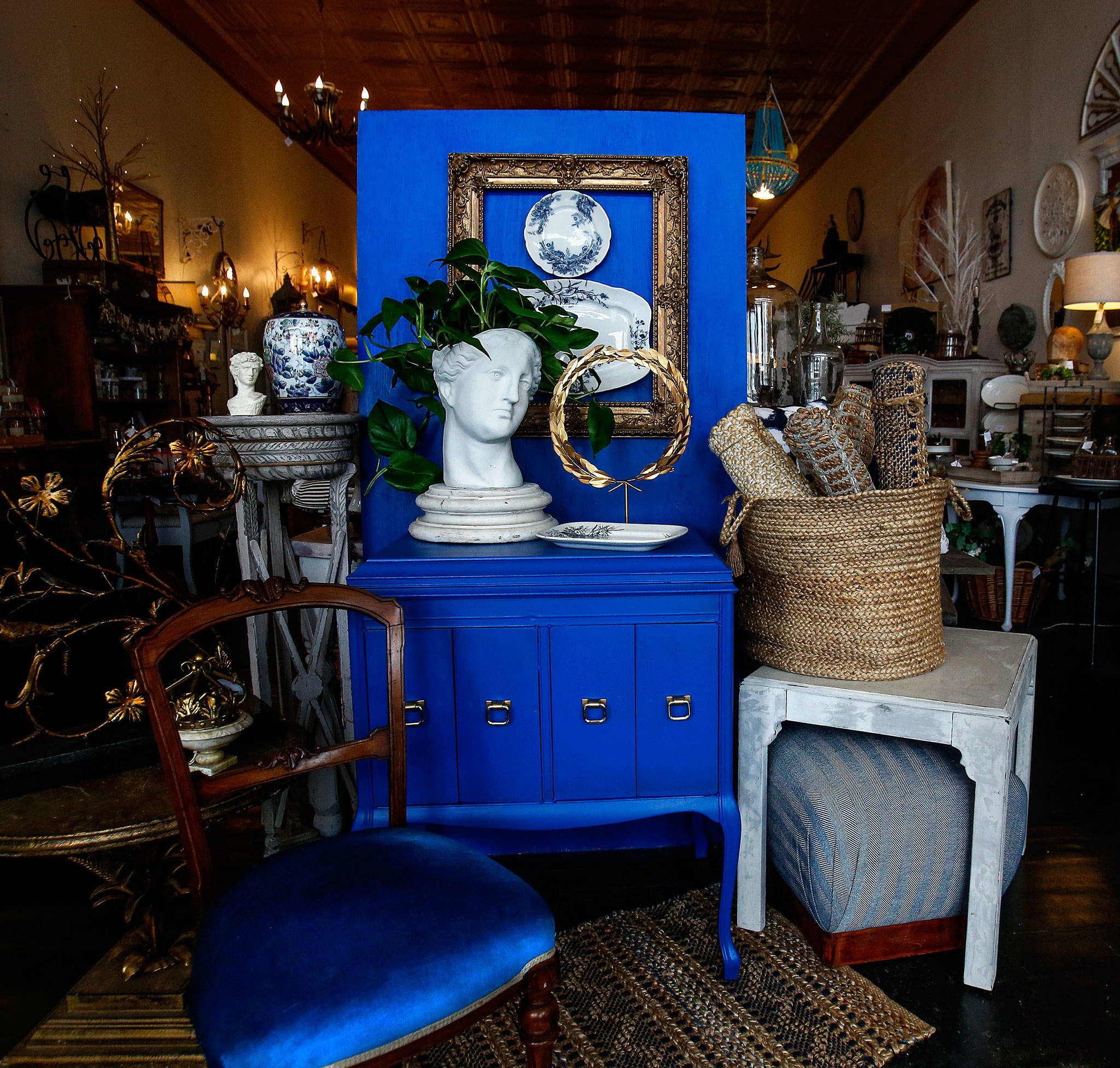 Interior designer Kelly DuByne shows off Pantone’s Color of the Year, classic blue, with a setting featuring an antique Victrola cabinet painted with the color and staged with neutral colors and strong white accents. (Dan Bates / The Herald)