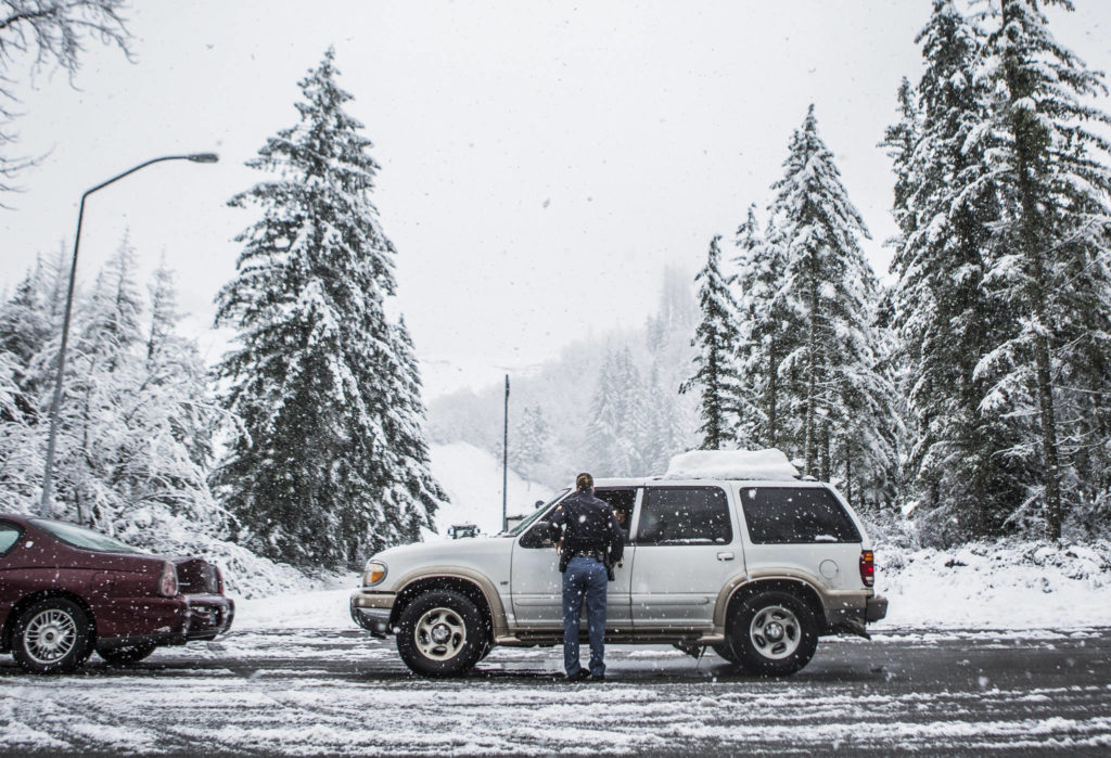 Washington State Patrol Trooper Heather Axtman talks to local residents hoping to get an escort into Index on Monday because U.S. 2 was closed to traffic. (Olivia Vanni / The Herald) 
