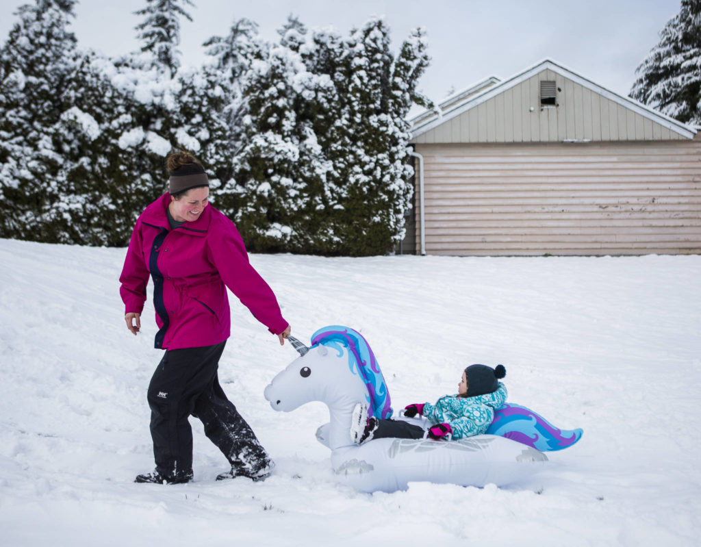 Audrey Boucock, 3, gets pulled in a makeshift unicorn blowup sled up the hill by her mother Laura Boucock on Monday in Everett. School was cancelled in the city because of at least a few inches of snow overnight. (Olivia Vanni / The Herald) 
