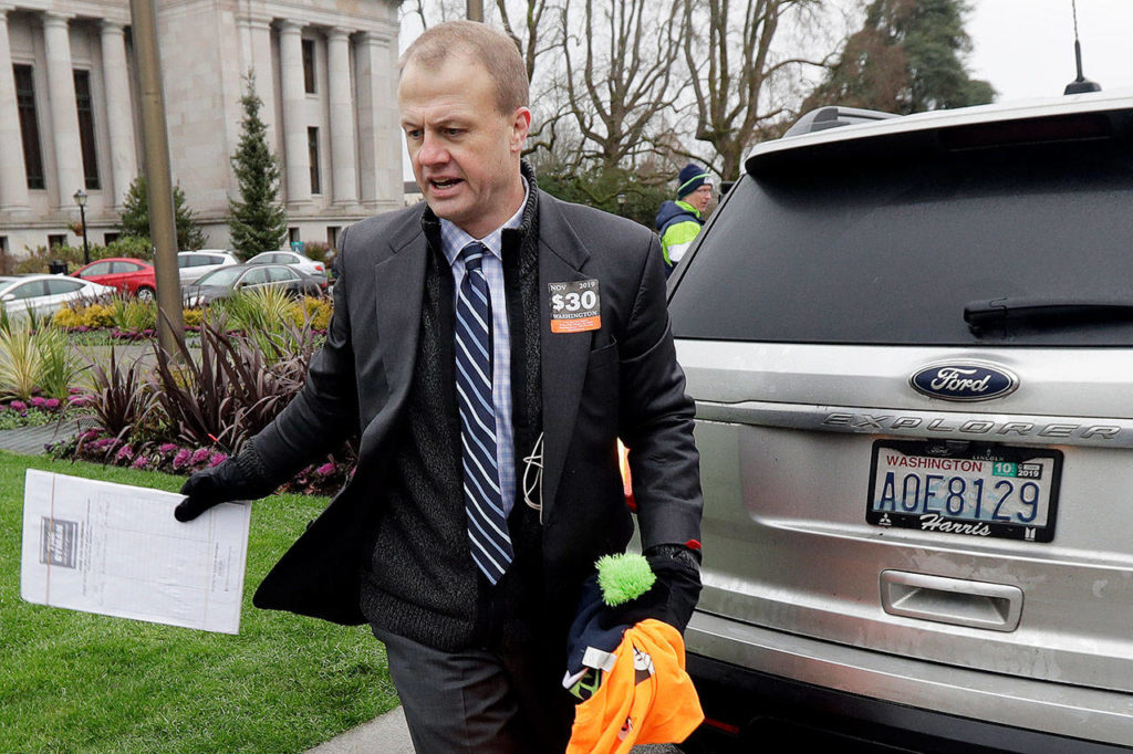 Initiative activist Tim Eyman, who is also running as an independent for Washington governor, walks next to his car (which has expired registration tabs) before attending a rally on the first day of the 2020 session of the Legislature at the Capitol in Olympia. (AP Photo/Ted S. Warren, File) 

