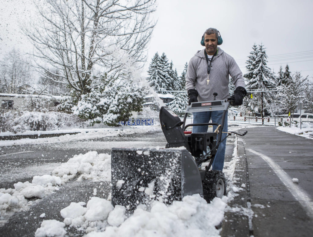 Brian Quantrille blows snow out of the parking lot of Seattle Hill Elementary on Wednesday in Everett. (Olivia Vanni / The Herald)
