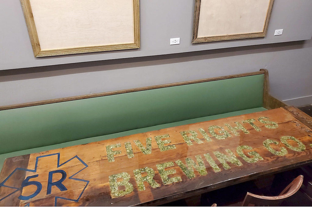 A table with Five Rights Brewing spelled out in hops sits in the new expanded space at the brewery in Marysville. 5 Rights’ employee Sean Seifert built the tables out of old Carr’s Hardware work benches. (Aaron Swaney)
