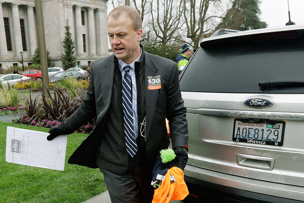 Initiative activist Tim Eyman, who is also running as an independent for Washington governor, carries a clipboard as he walks next to his expired car registration tabs before attending a rally Jan. 13 on the first day of the 2020 session of the Washington Legislature in Olympia. (AP Photo/Ted S. Warren, File)