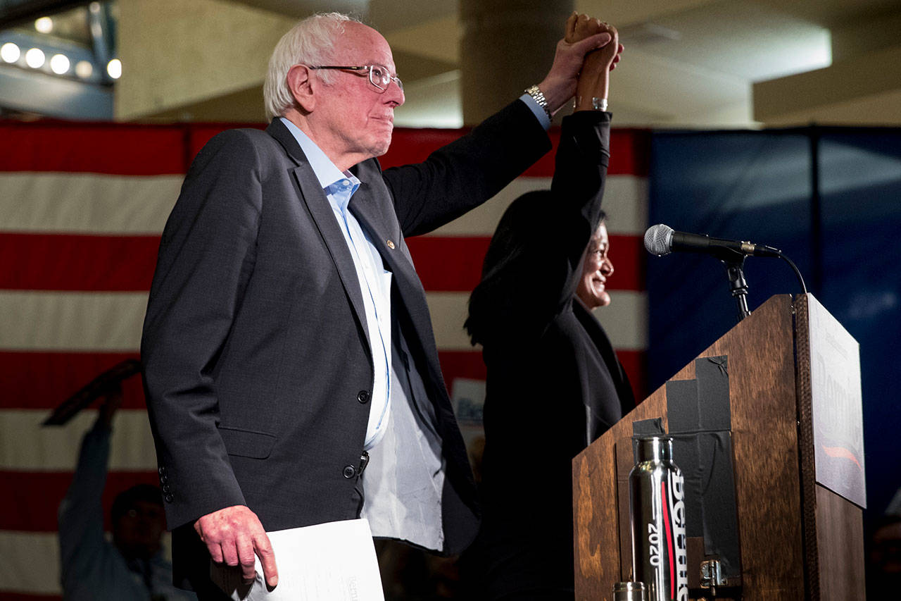 Democratic presidential candidate Sen. Bernie Sanders holds hands on stage with Rep. Pramila Jayapal as he arrives to speak at a campaign stop at the State Historical Museum of Iowa on Monday in Des Moines, Iowa. (AP Photo/Andrew Harnik)