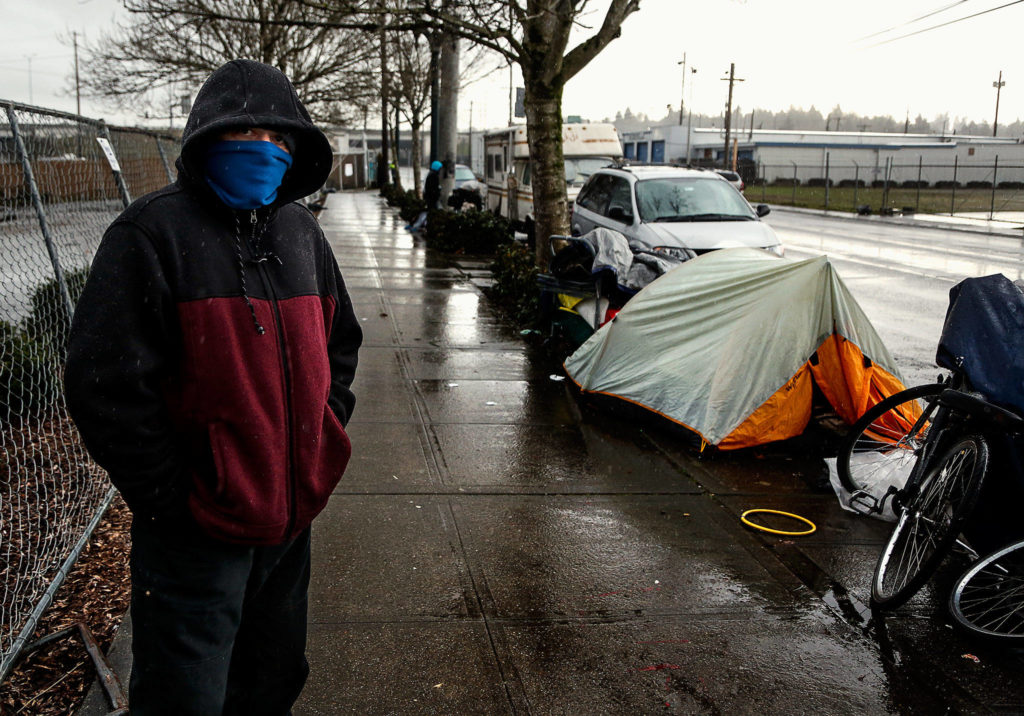 A young man passes time at a spot where people have camped along Smith Avenue north of the Everett Gospel Mission and south of Everett Station, Tuesday. (Dan Bates / The Herald)
