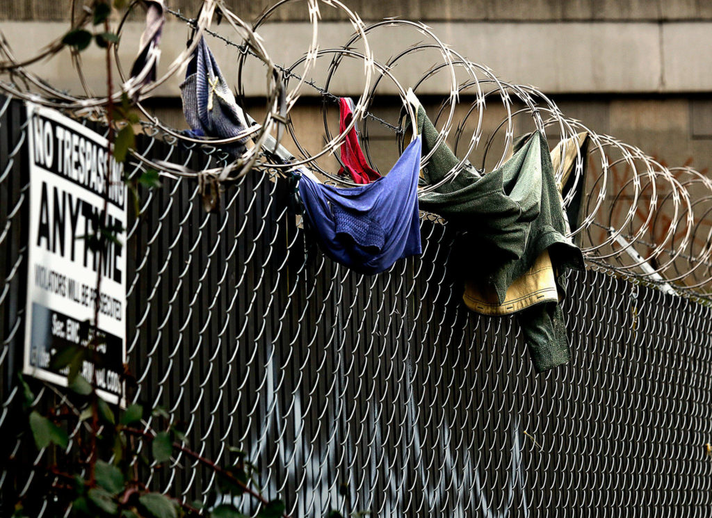 A number of trespassers have given up their shirts and other articles of clothing attempting to climb over razor wire at a fenced location near the Everett Gospel Mission on Smith Avenue in Everett. (Dan Bates / The Herald)
