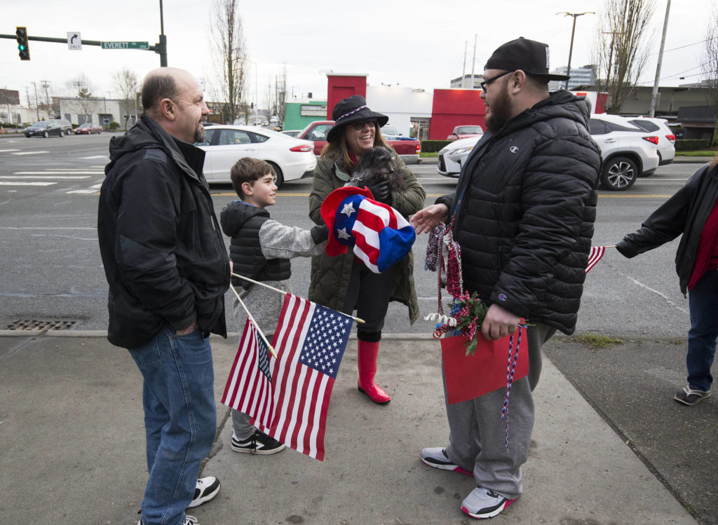 Vincent Grieci offers his hat to Vili Bloomfield, the son of Samiu Bloomfield, as friends and fans gather on Broadway to wave in honor of Samiu on Monday in Everett. Bloomfield , who died Sunday, was known for waving the American flag and the tattoos that covered his face and body. (Andy Bronson / The Herald)
