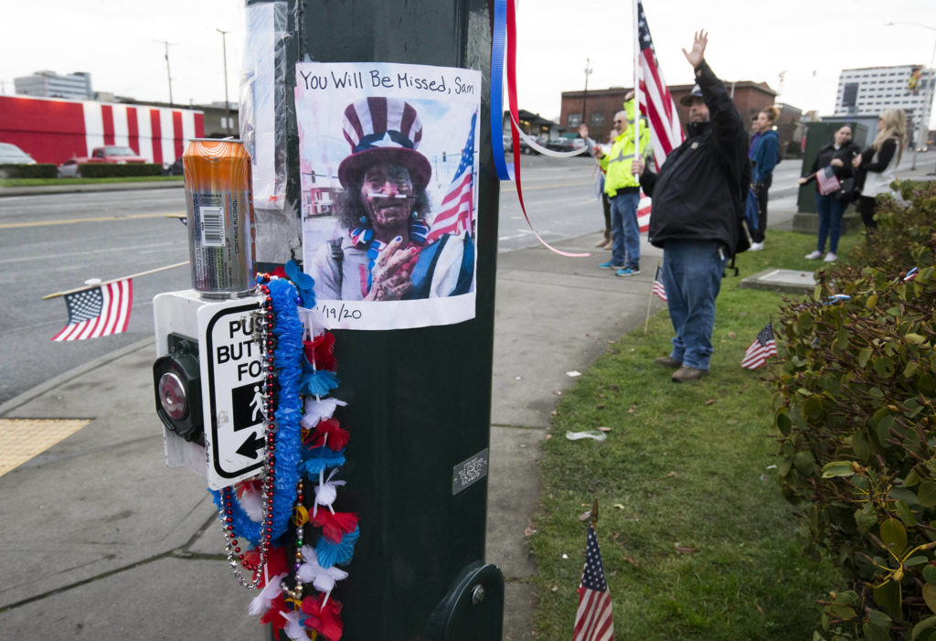A photo of Samiu Bloomfield is taped to a pole where his friends and fans gather on Broadway to wave in his honor Monday in Everett. (Andy Bronson / The Herald)
