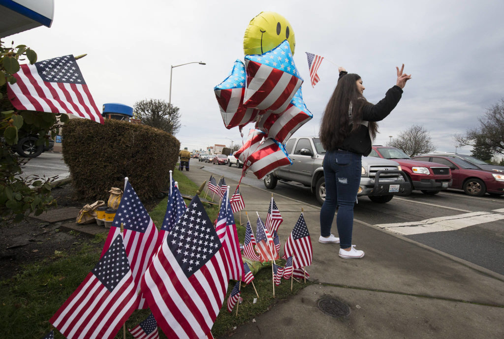 Samiu Bloomfield’s cousin Candice Candice Fakatoufifita-White waves a flag and shows a peace sign as friends and fans gather on Broadway to wave in Samiu’s honor on Monday in Everett. (Andy Bronson / The Herald)
