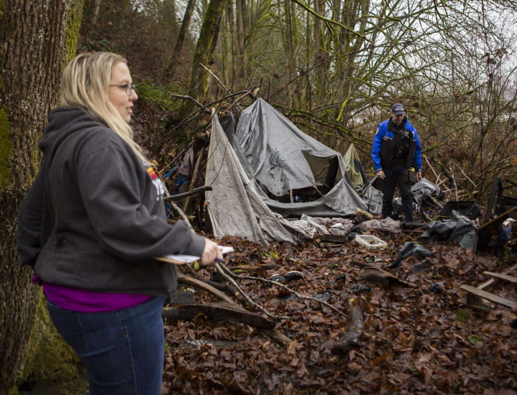 Everett police officer Shane Nelson walks away from an empty encampment in Everett during the annual Point-in-Time Count on Thursday. (Olivia Vanni / The Herald)
