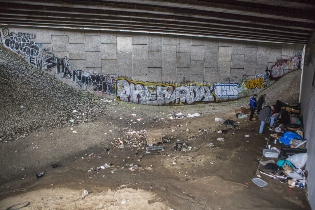 Everett police officers and social workers talk with people experiencing homelessness in the area known as “The Pit” on Thursday. (Olivia Vanni / The Herald)
