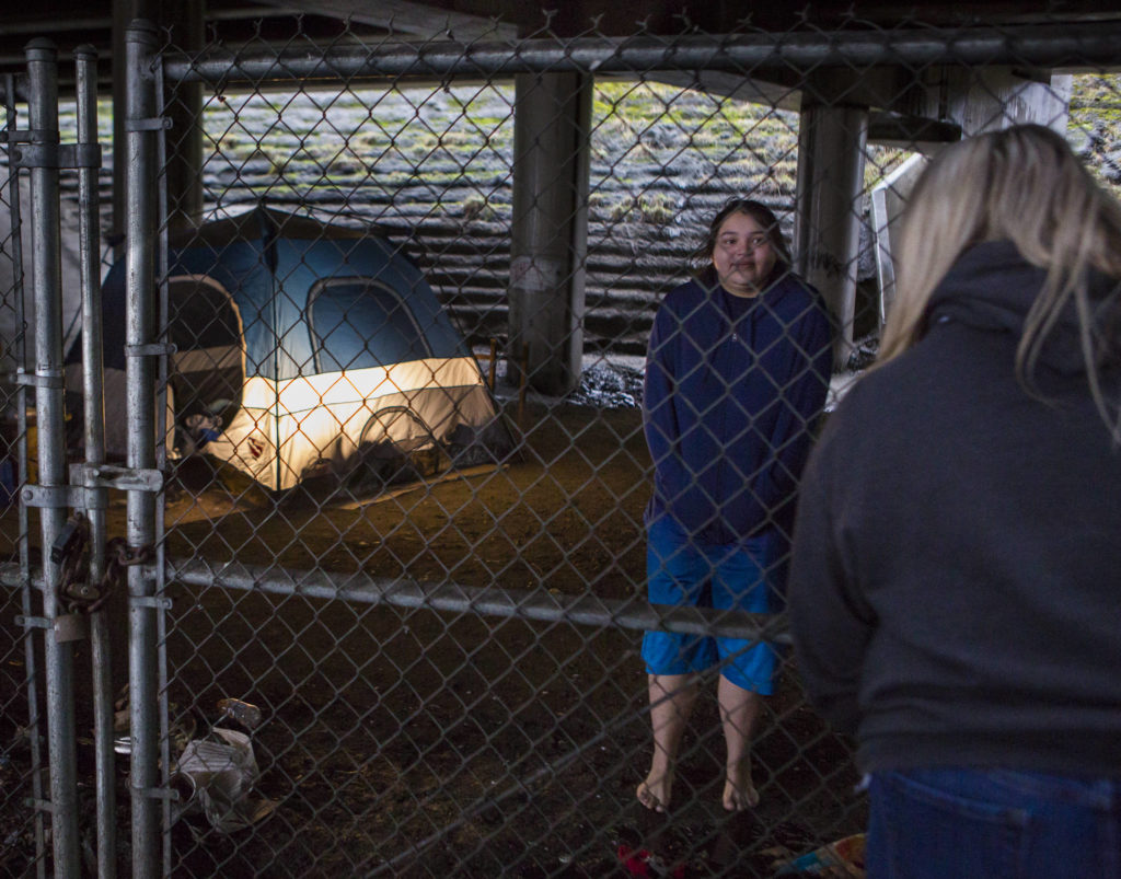 Snohomish County social worker Amanda Jeffcott talks with two people living in an area known as “The Bat Caves” on Thursday. (Olivia Vanni / The Herald)
