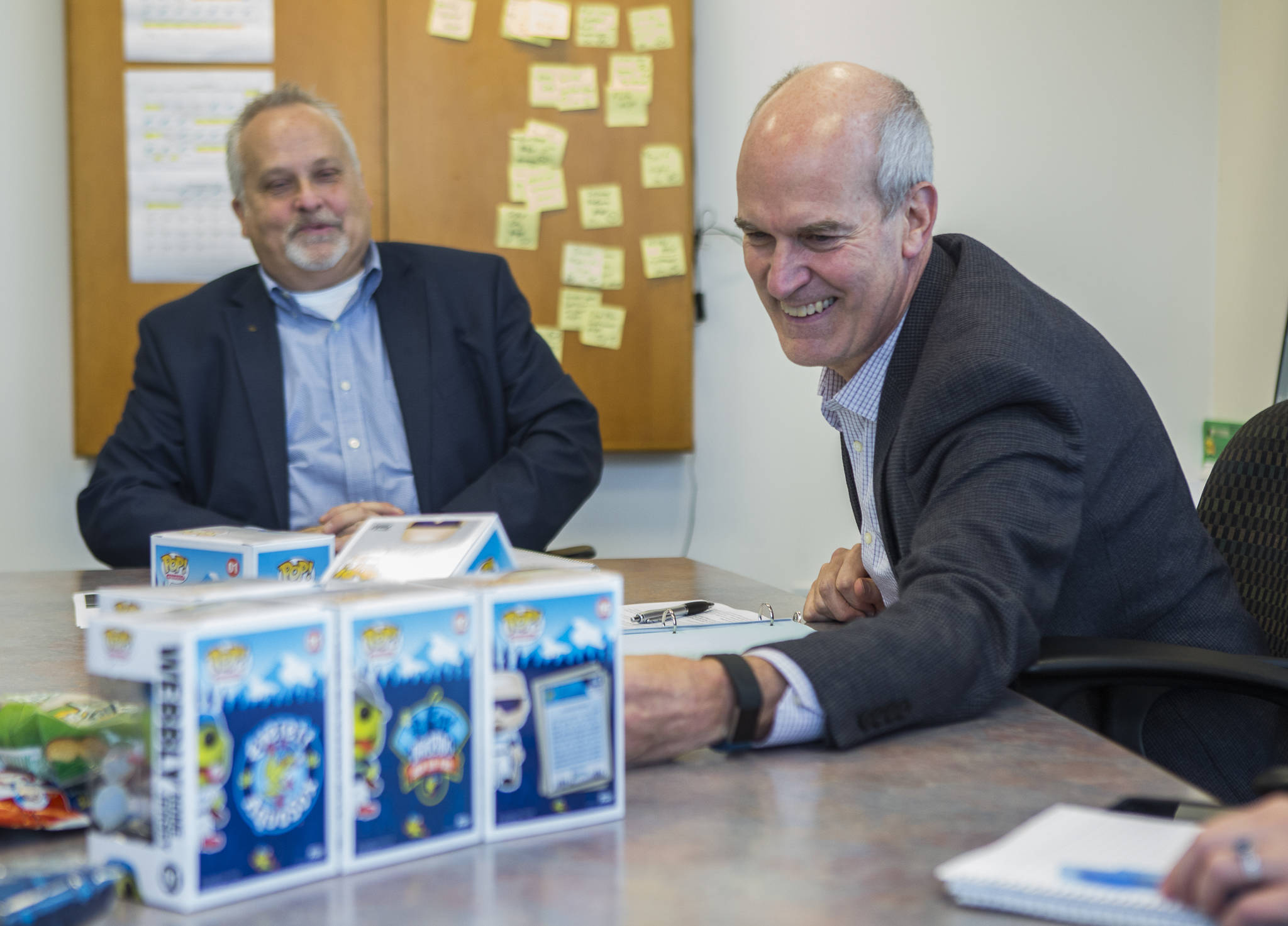 Washington State congressman Rick Larsen (right) smiles while looking at a Webbly Funko POP! during a meeting with Aquasox general manager Danny Tetzlaff (left) on Tuesday in Everett. (Olivia Vanni / The Herald)