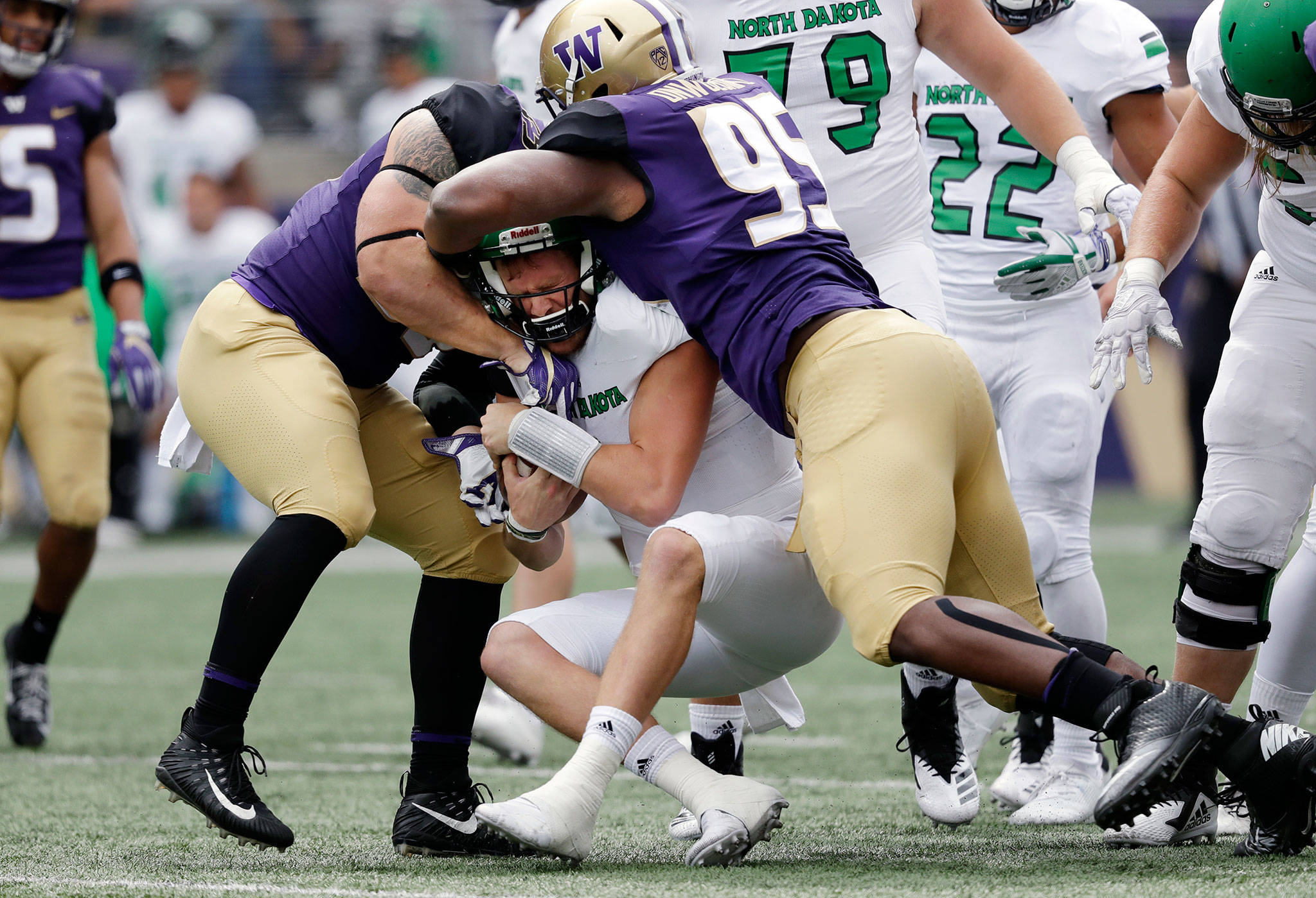 Washington’s Ryan Bowman (left) and Levi Onwuzurike (right) wrap-up North Dakota quarterback Nate Ketteringham during a game on Sept. 8, 2018, in Seattle. (AP Photo/Elaine Thompson)