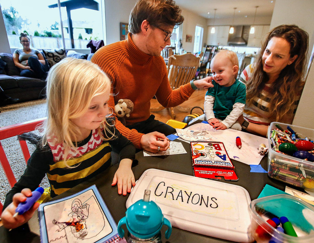Bianca Hertl, 4, concentrates on her art as her mother, Leah Hertl, and baby brother Owen, 1, talk with the Edmonds family’s au pair, Rico Baumgardt. Chosen as a finalist for an agency’s Au Pair of the Year Award, Baumgardt will soon return to his homeland of Germany. (Dan Bates / The Herald)
