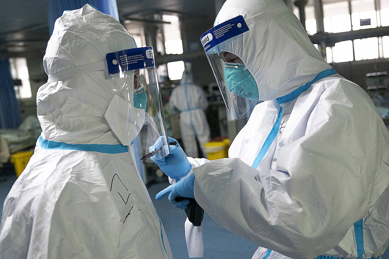 A medical worker writes their colleague’s name on a protective suit to aid in identification as they work at Zhongnan Hospital of Wuhan University in Wuhan in central China’s Hubei Province on Friday. (Xiong Qi/Xinhua via AP)