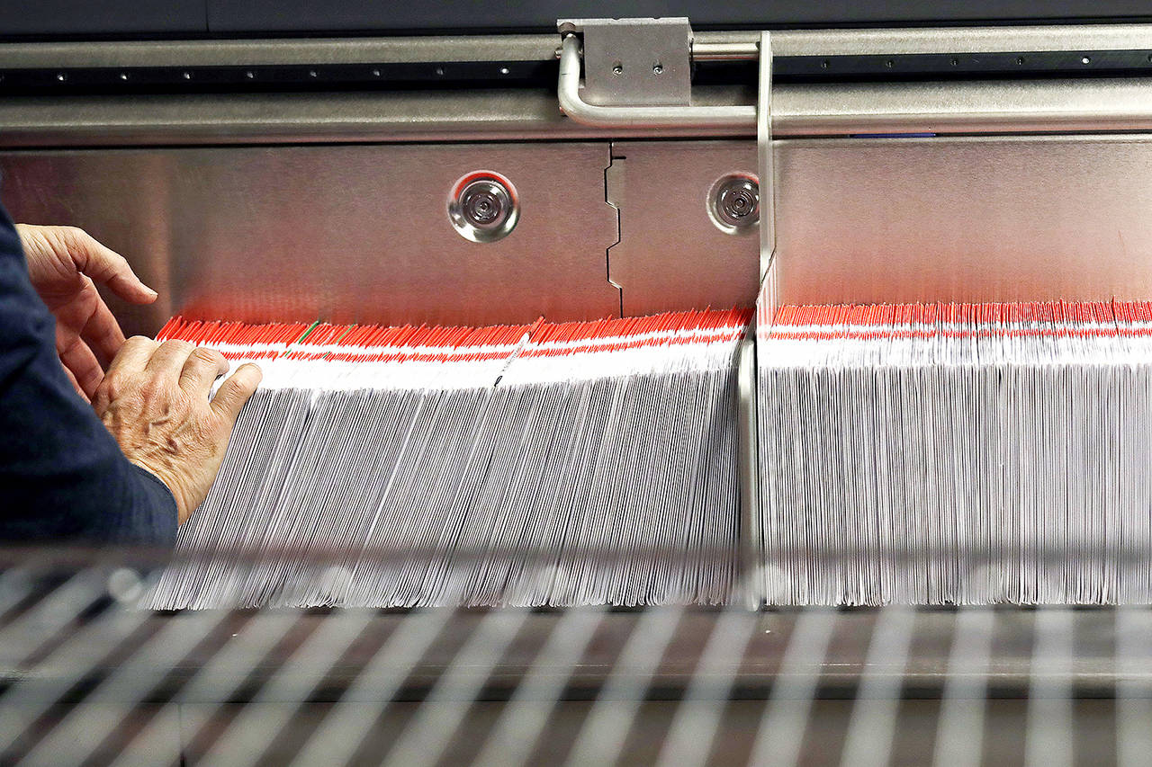 This 2018 photo shows an election worker stacking ballots into a sorting machine at the King County Elections office in Renton. (AP Photo/Elaine Thompson, File)