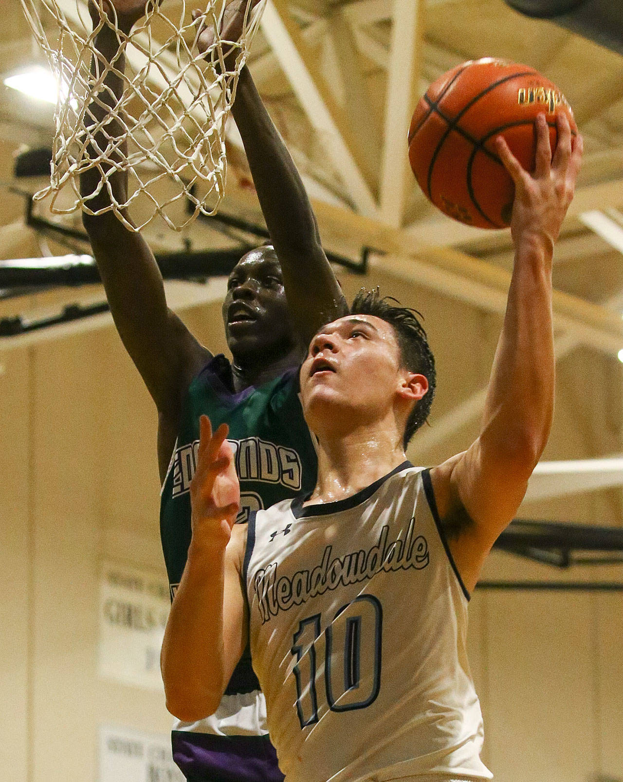 Meadowdale’s Colton Walsh (10) attempts a layup with Edmonds-Woodway’s Nuer Bol defending Friday evening at Meadowdale High School in Lynnwood. Meadowdale won 64-53. (Kevin Clark / The Herald)