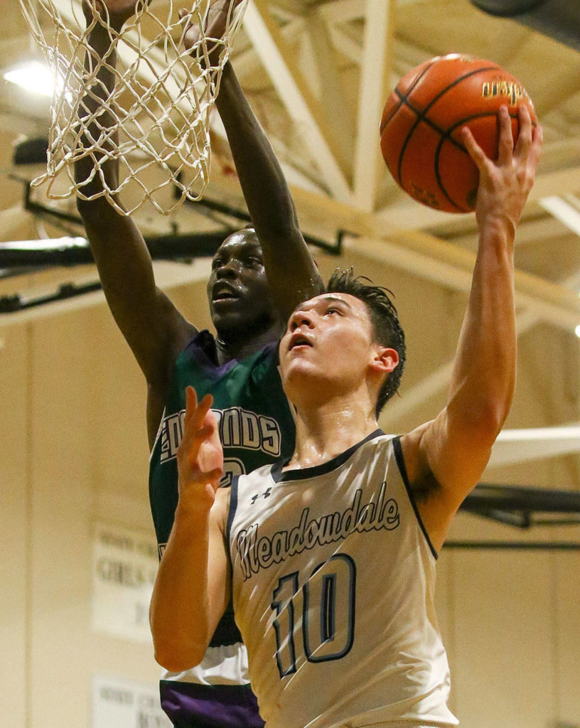 Meadowdale’s Colton Walsh (10) attempts a layup with Edmonds-Woodway’s Nuer Bol defending Friday evening at Meadowdale High School in Lynnwood. Meadowdale won 64-53. (Kevin Clark / The Herald)

