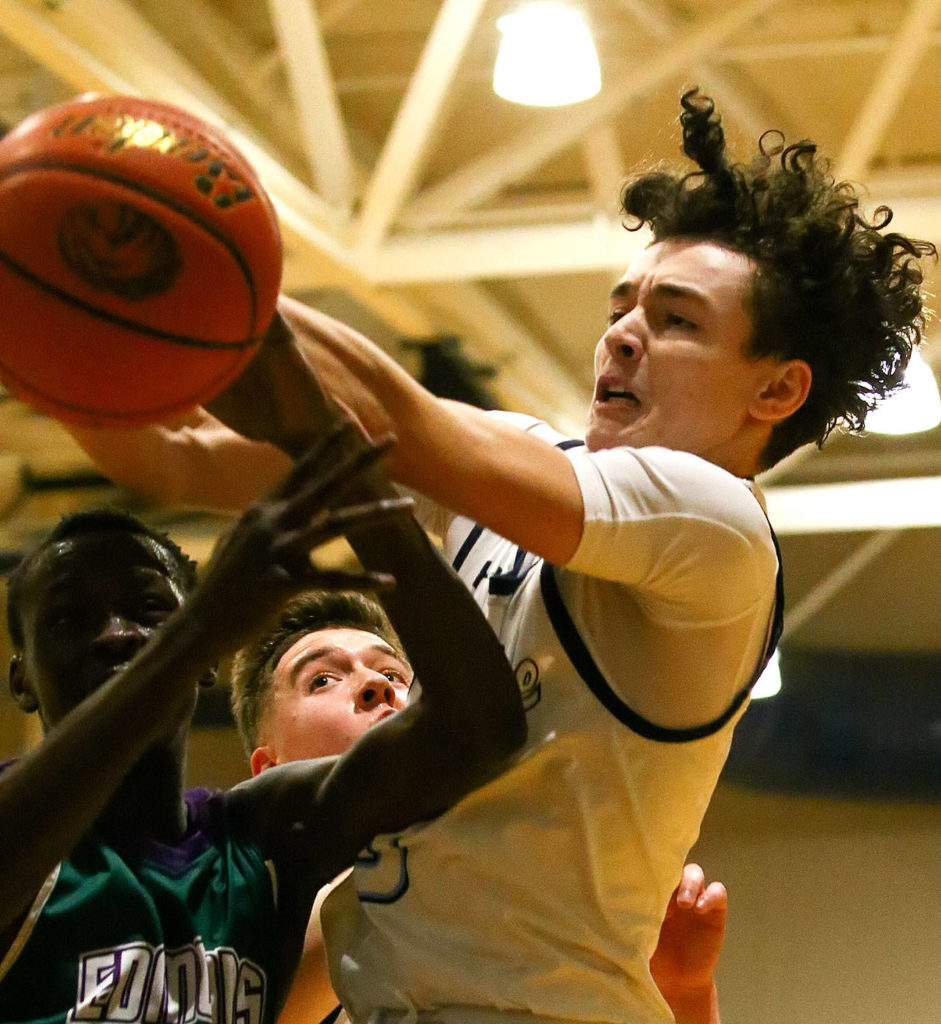 Meadowdale’s Justin Jackson (right) and Edmonds-Woodway’s Nuer Bol fight for a rebound Friday evening at Meadowdale High School in Lynnwood January 24, 2019. (Kevin Clark / The Herald)
