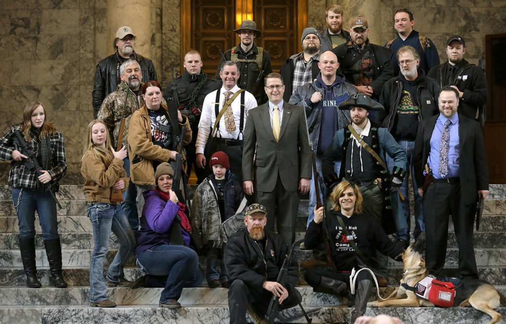 In this 2015 photo, Washington state Rep. Matt Shea (in suit and yellow tie at center) poses for a group photo with gun owners inside the Capitol in Olympia following a gun-rights rally. (AP Photo/Ted S. Warren, File)
