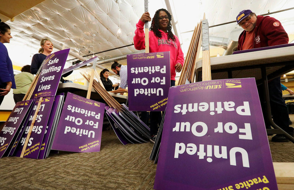 Valarie Howard (second from right), a certified nursing assistant at Swedish First Hill, makes picket signs in Seattle on Monday as they plan to strike Tuesday. (Ken Lambert/The Seattle Times via AP)
