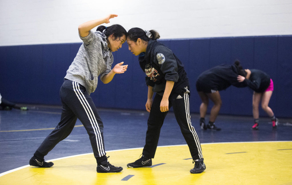 Everett’s Sumina Gurung (left) works with teammate Craydi Moen during wrestling practice on Monday in Everett. Gurung is a sophomore born in Nepal and Moen, a senior, was born in Mexico and moved to America at around age 8. (Andy Bronson / The Herald)
