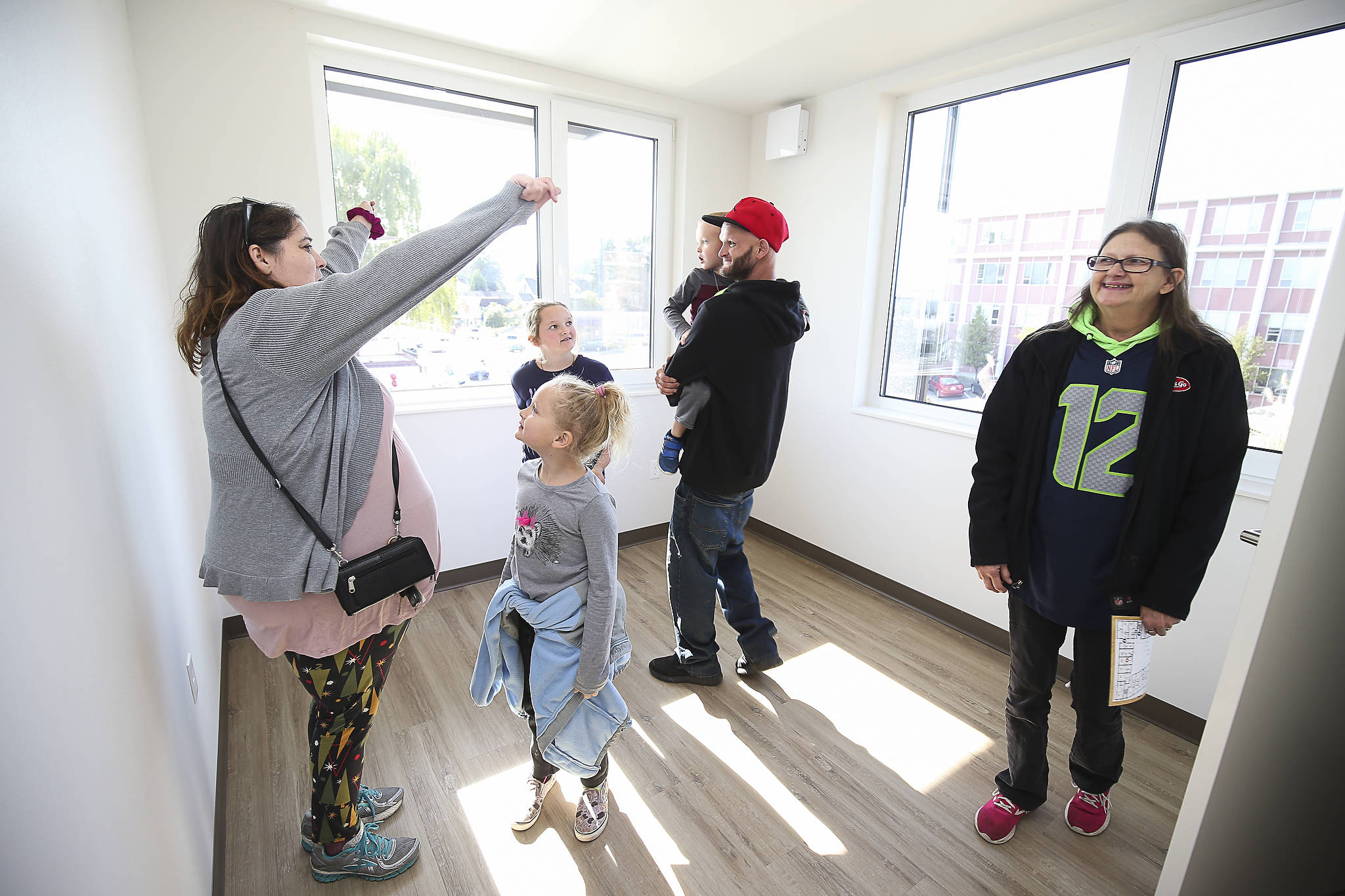 Lisa Collier (left) cheers for her cousin Andrew Pliss (in the red hat) as they tour a two-bedroom apartment where Andrew will live with his children, Riley and Chelsea, at HopeWorks Station, in October, in Everett. The newly opened building offers 65 units for formerly homeless families, veterans and young adults. Housing Hope, affiliated with HopeWorks, has proposed a similar supportive housing complex for the families of homeless students near Sequoia High School. (Andy Bronson / Herald file photo)