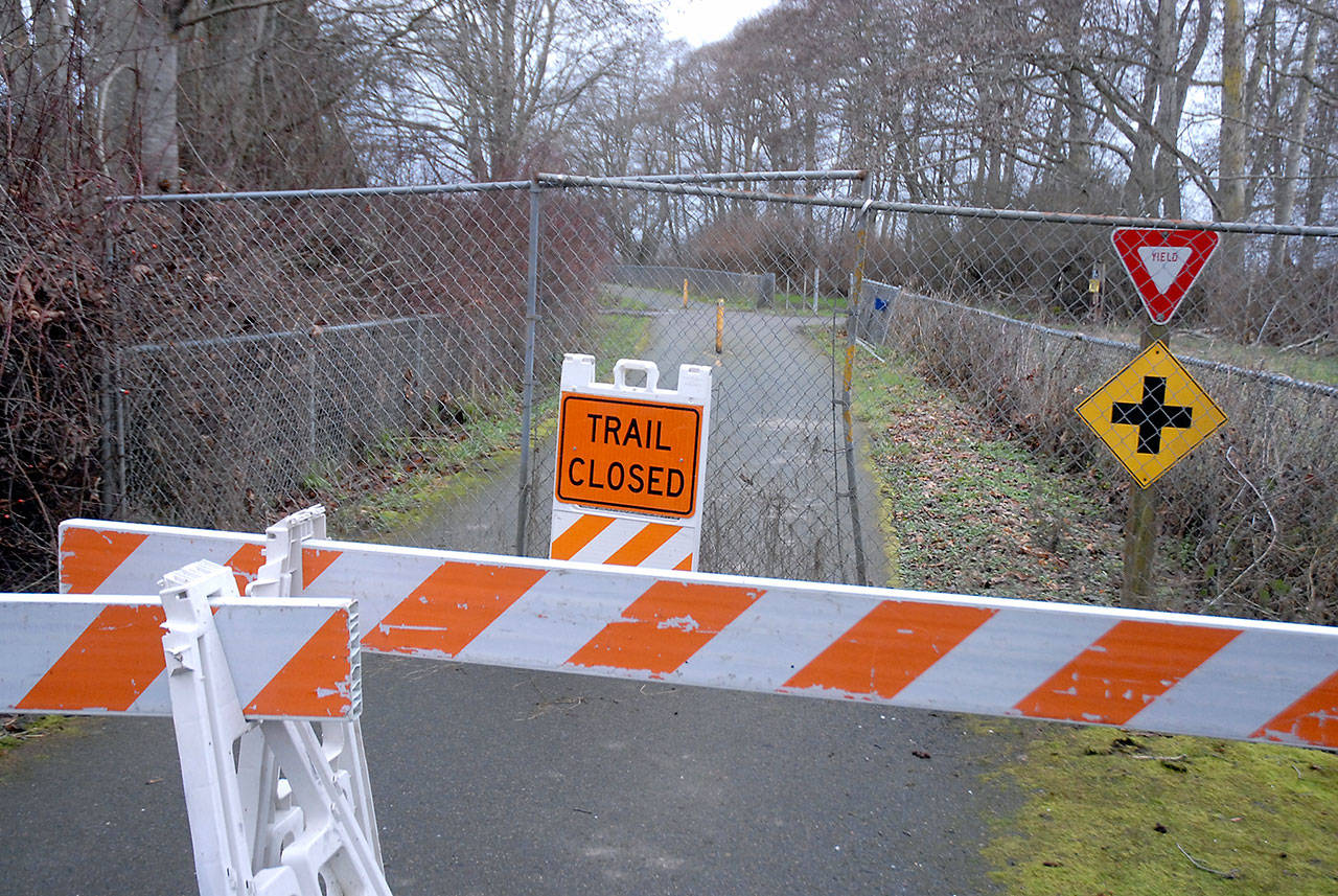 Barricades, construction fencing and a warning sign block a section of the Olympic Discovery Trail near Four Seasons Ranch east of Port Angeles at the site where human remains were discovered near a storm-damaged portion of the trail. (Keith Thorpe/Peninsula Daily News)