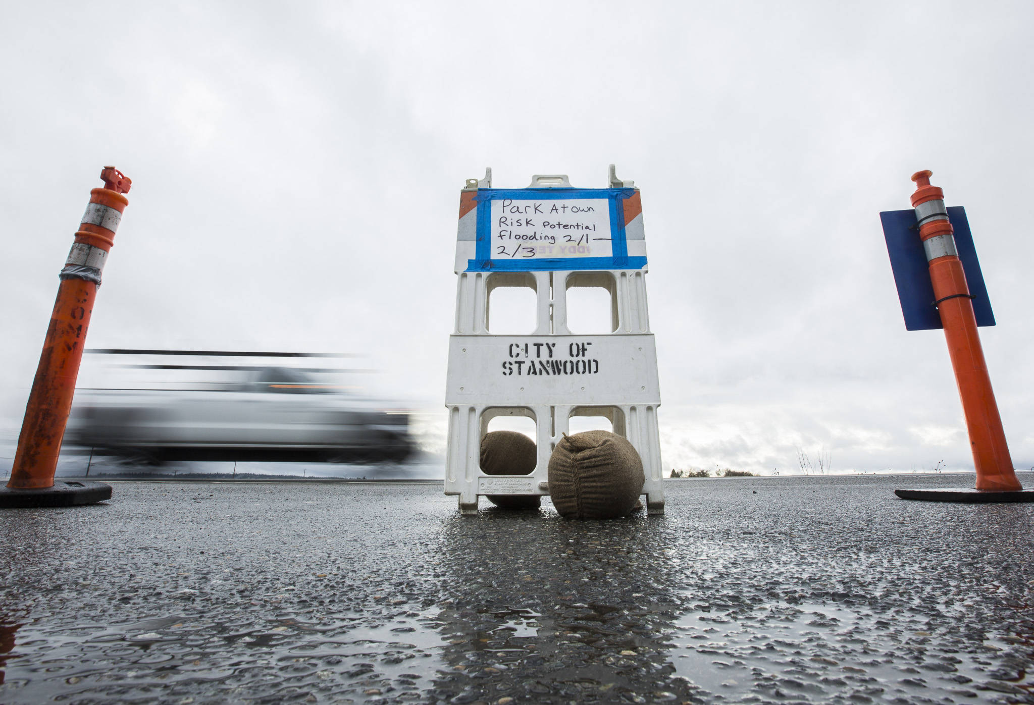 A car drives by a closed Stanwood II Park & Ride entrance with a sign that reads, “Park at own risk potential flooding 2/1 - 2/3” off of 267th Street on Friday in Stanwood. (Olivia Vanni / The Herald)