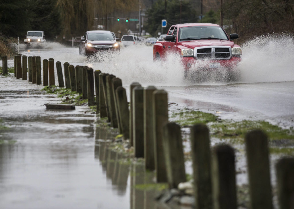 A truck drives through water running over State Route 530 next to Twin Rivers County Park on Saturday in Arlington. (Olivia Vanni / The Herald)
