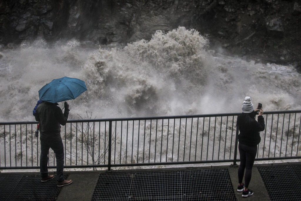 People watch and take photos of the water rushing through the Granite Falls Fish Ladder on Saturday in Granite Falls. (Olivia Vanni / The Herald)
